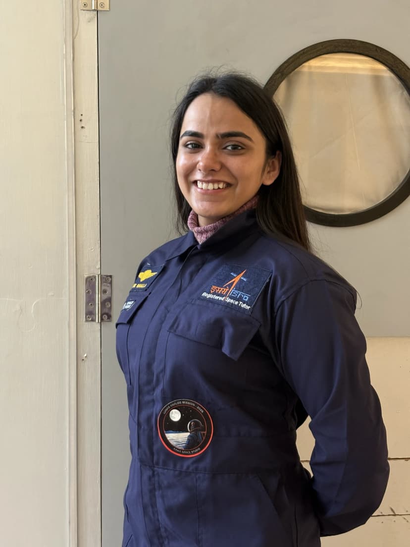 Annie Bhalla in flight suit in front of space capsule